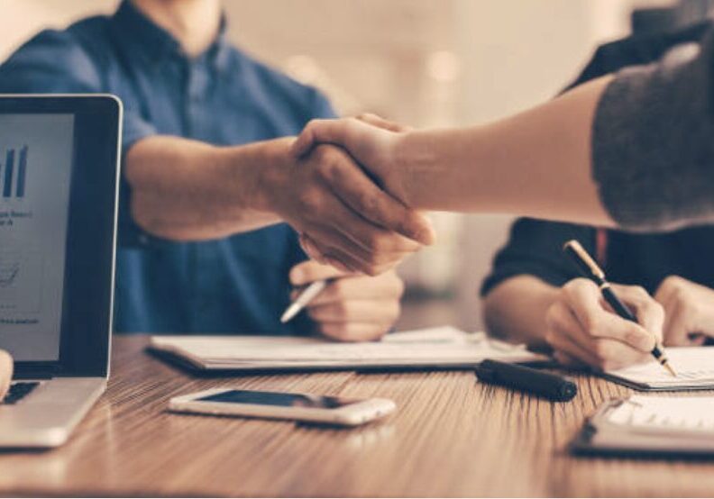 People sitting at table shaking hands